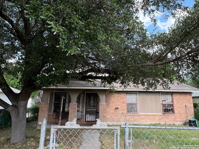 bungalow-style house with covered porch, brick siding, and a fenced front yard