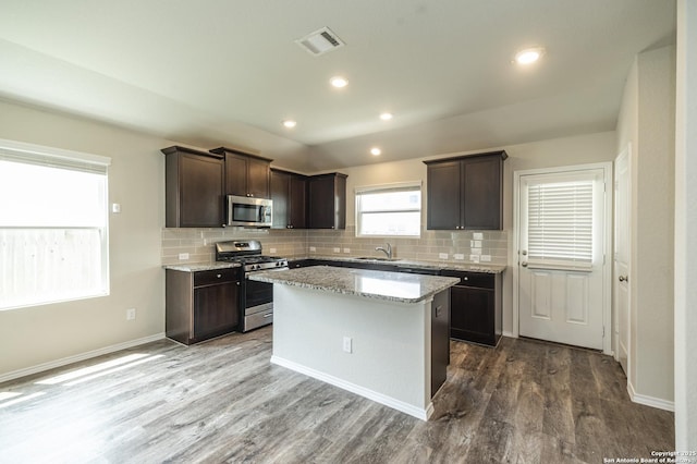 kitchen with visible vents, dark brown cabinetry, a sink, appliances with stainless steel finishes, and backsplash