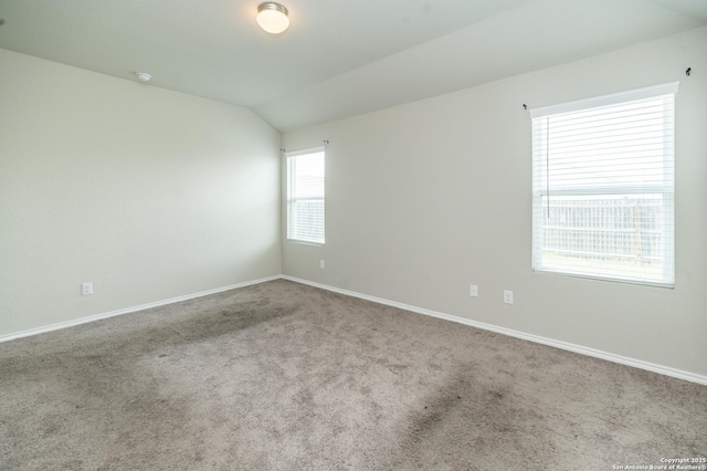 empty room with carpet floors, baseboards, and lofted ceiling
