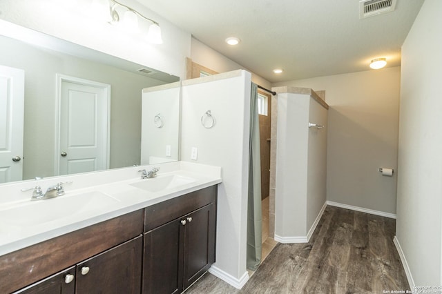 full bathroom featuring visible vents, a sink, and wood finished floors