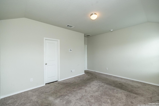 spare room with visible vents, carpet flooring, baseboards, and lofted ceiling
