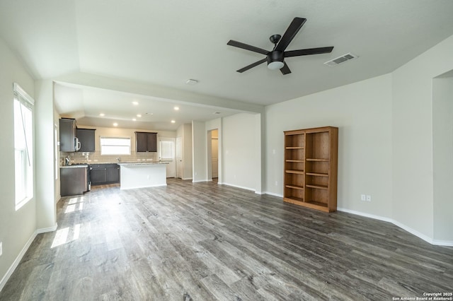 unfurnished living room featuring visible vents, a ceiling fan, baseboards, and wood finished floors