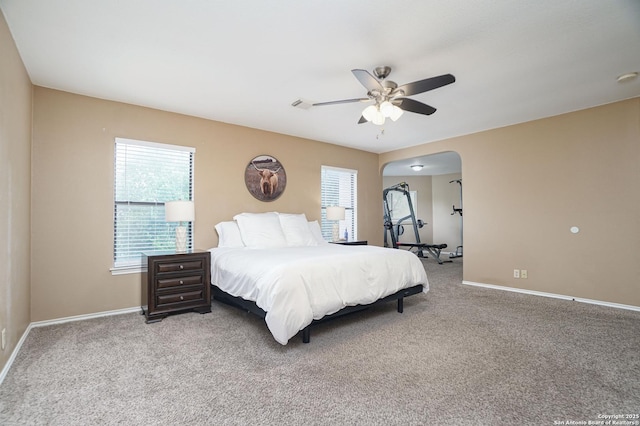 bedroom with carpet floors, arched walkways, and baseboards