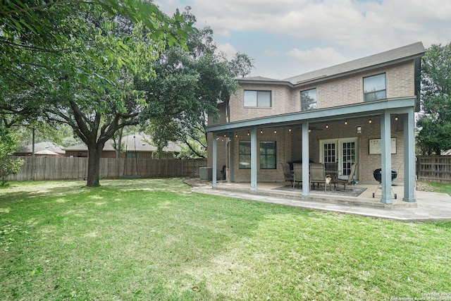 rear view of house featuring a lawn, brick siding, a patio, and a fenced backyard