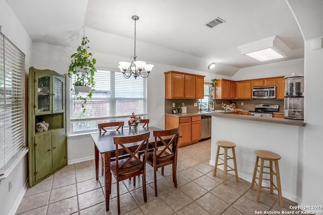 kitchen featuring a kitchen breakfast bar, a chandelier, stainless steel appliances, lofted ceiling, and visible vents