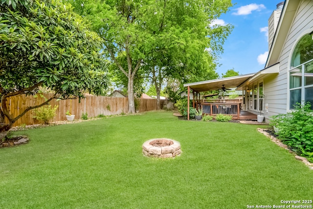 view of yard featuring a fenced backyard, ceiling fan, and a fire pit