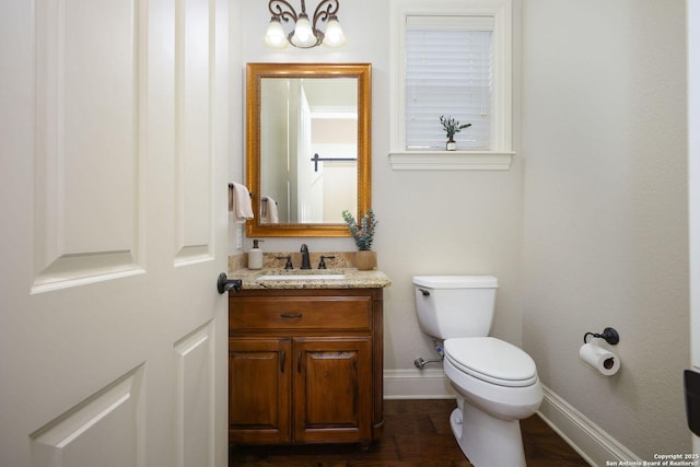 bathroom featuring toilet, baseboards, wood finished floors, and vanity