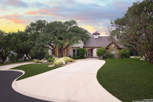 view of front facade featuring curved driveway, a front lawn, and stone siding
