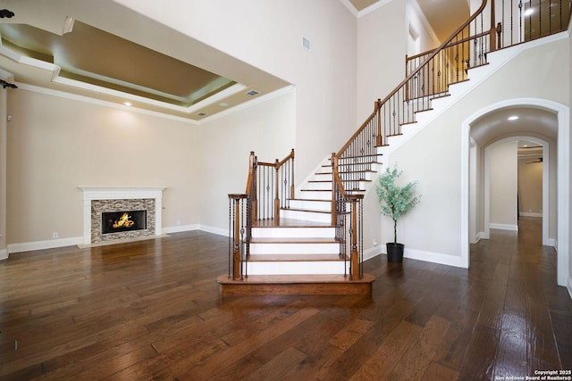 staircase with visible vents, crown molding, arched walkways, baseboards, and hardwood / wood-style floors