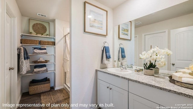 bathroom with visible vents, vanity, wood finished floors, baseboards, and a stall shower