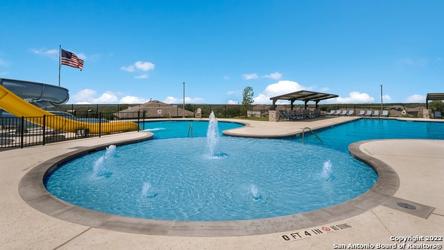 pool with fence, a water slide, and a patio area