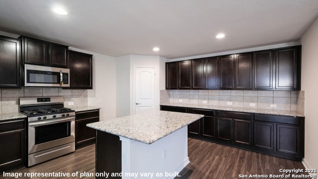 14610 Clay Ridge Run, San Antonio, TX 78253 - kitchen featuring light stone counters, dark wood finished floors, a center island, stainless steel appliances, and tasteful backsplash