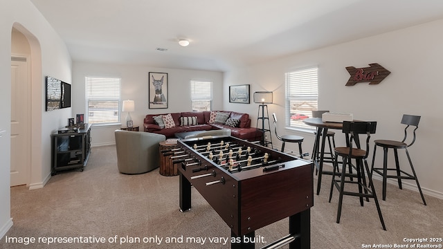 rec room with carpet floors, plenty of natural light, baseboards, and arched walkways