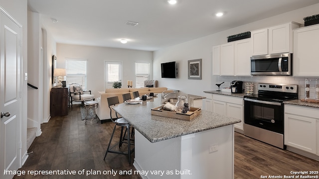 kitchen with decorative backsplash, dark wood-style flooring, an island with sink, white cabinetry, and appliances with stainless steel finishes