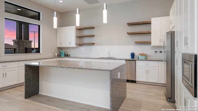 kitchen with a sink, open shelves, and light wood-style flooring