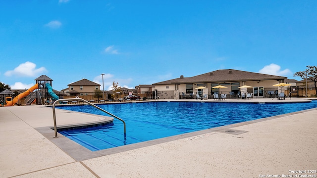pool with playground community, fence, and a patio area
