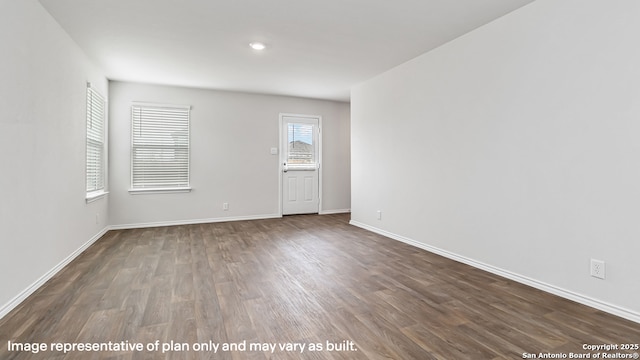 spare room with baseboards and dark wood-style floors