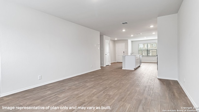 unfurnished living room featuring visible vents, wood finished floors, a sink, baseboards, and recessed lighting