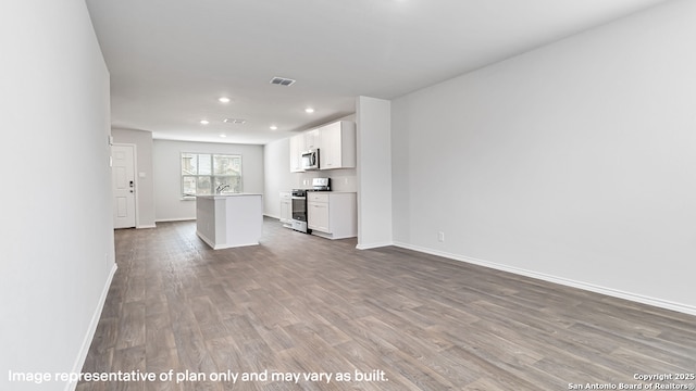 unfurnished living room featuring visible vents, wood finished floors, a sink, baseboards, and recessed lighting