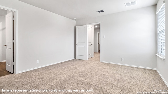 unfurnished bedroom featuring baseboards, carpet flooring, and visible vents