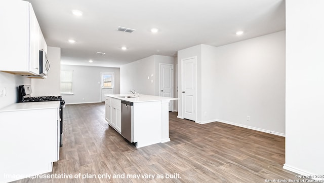 kitchen featuring appliances with stainless steel finishes, an island with sink, light wood-style flooring, white cabinetry, and visible vents