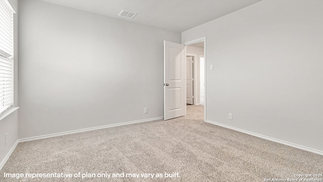 spare room featuring baseboards, visible vents, and light carpet
