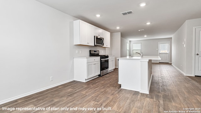kitchen featuring a kitchen island with sink, dark wood-style flooring, visible vents, appliances with stainless steel finishes, and light countertops