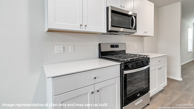 kitchen with white cabinets, appliances with stainless steel finishes, light countertops, light wood-style flooring, and baseboards