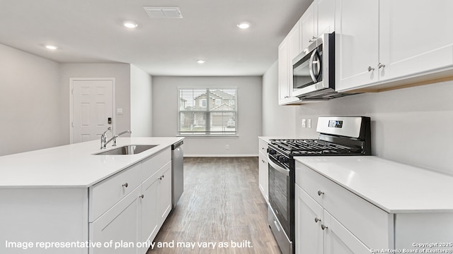 kitchen featuring visible vents, wood finished floors, a sink, light countertops, and stainless steel appliances