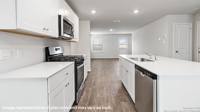 kitchen featuring appliances with stainless steel finishes, wood finished floors, a sink, light countertops, and white cabinetry
