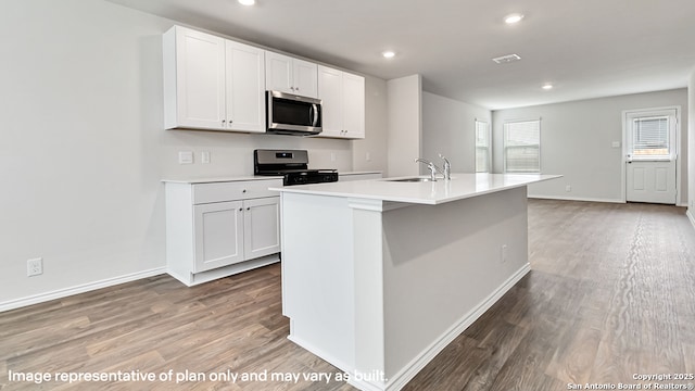 kitchen with white cabinets, appliances with stainless steel finishes, a sink, light wood-style floors, and light countertops