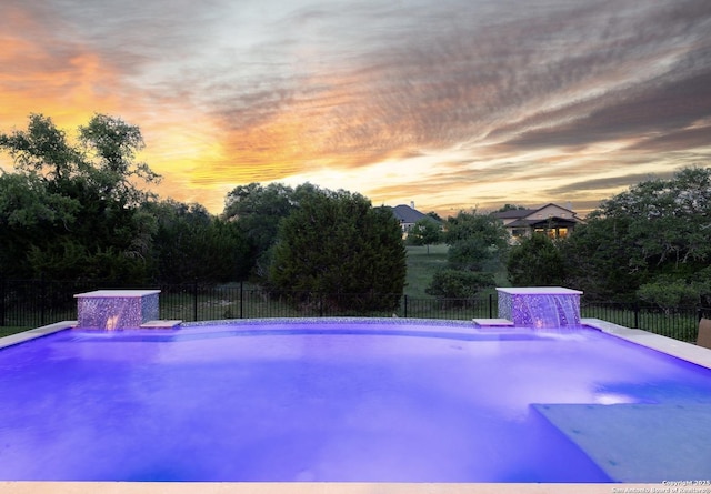 pool at dusk with fence and a fenced in pool