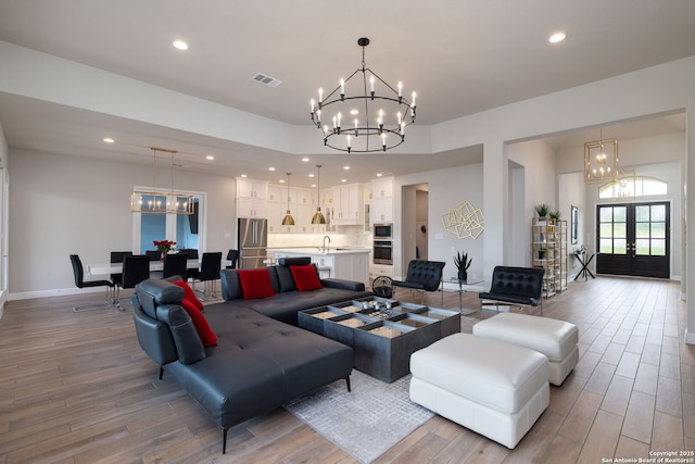living room featuring recessed lighting, a notable chandelier, light wood-style flooring, and visible vents