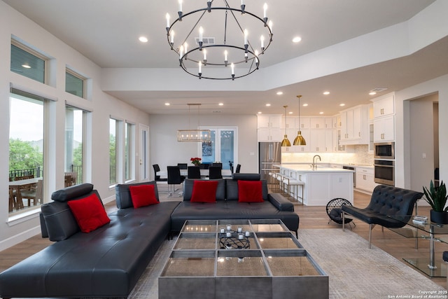 living room featuring an inviting chandelier, recessed lighting, wood finished floors, and visible vents