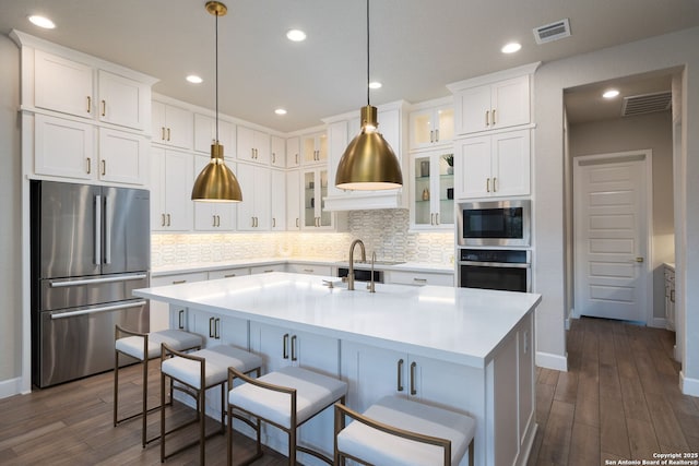 kitchen featuring visible vents, light countertops, dark wood finished floors, appliances with stainless steel finishes, and backsplash