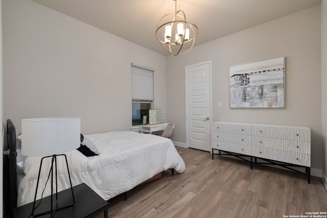 bedroom featuring baseboards, wood finished floors, and a chandelier
