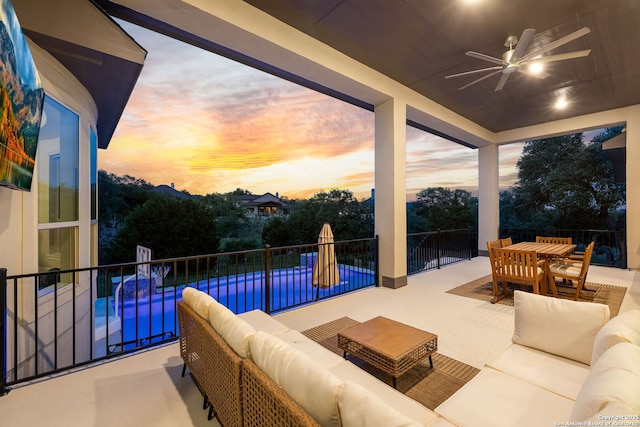 patio terrace at dusk featuring ceiling fan, outdoor lounge area, outdoor dining space, and a pool