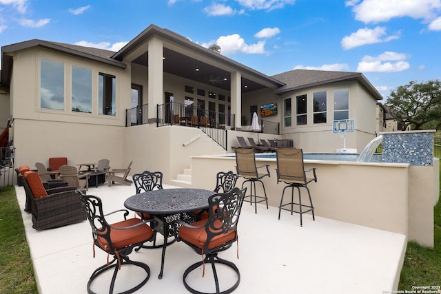back of property featuring stucco siding, outdoor dry bar, stairs, a ceiling fan, and a patio area