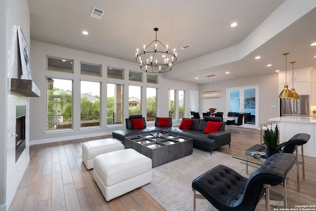 living area with an inviting chandelier, light wood-style floors, recessed lighting, and visible vents