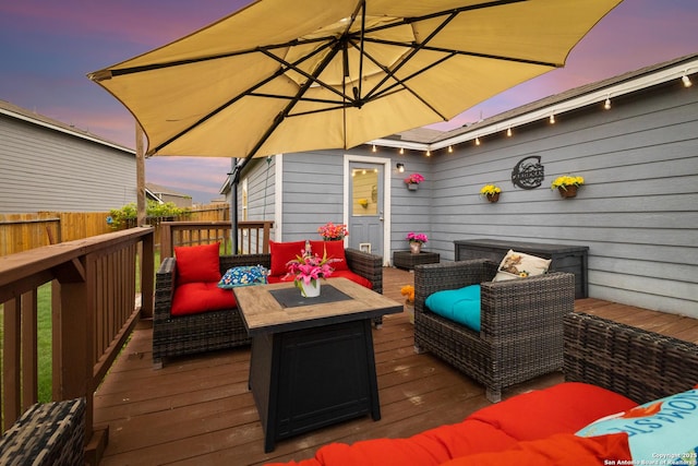 deck at dusk with fence and an outdoor living space