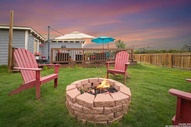yard at dusk featuring fence and a fire pit