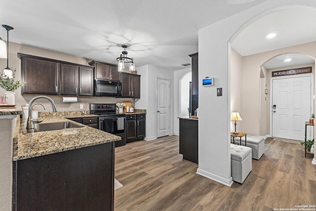 kitchen with black microwave, dark brown cabinets, electric range oven, arched walkways, and a sink