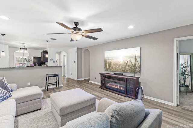 living room with a glass covered fireplace, arched walkways, wood finished floors, and visible vents