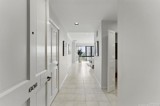 hallway featuring light tile patterned floors, baseboards, and recessed lighting