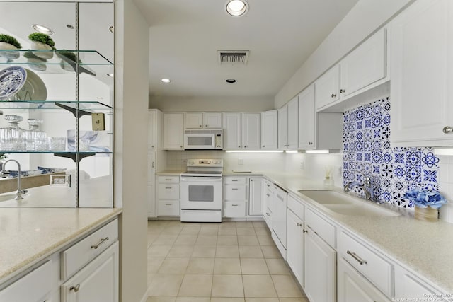 kitchen featuring white cabinets, a sink, white appliances, light tile patterned floors, and visible vents