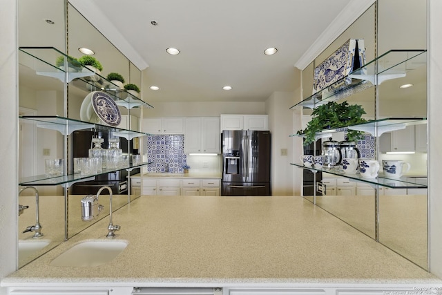 kitchen with decorative backsplash, black fridge with ice dispenser, a sink, white cabinets, and recessed lighting
