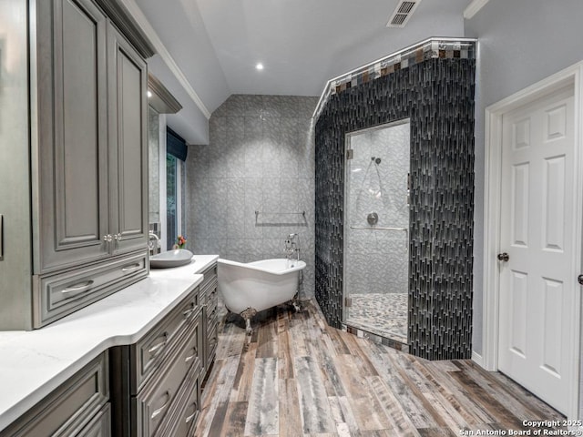 full bathroom featuring visible vents, vanity, a freestanding tub, tile walls, and walk in shower