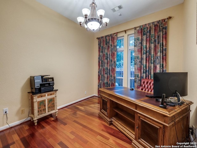 office space featuring baseboards, a notable chandelier, wood finished floors, and visible vents