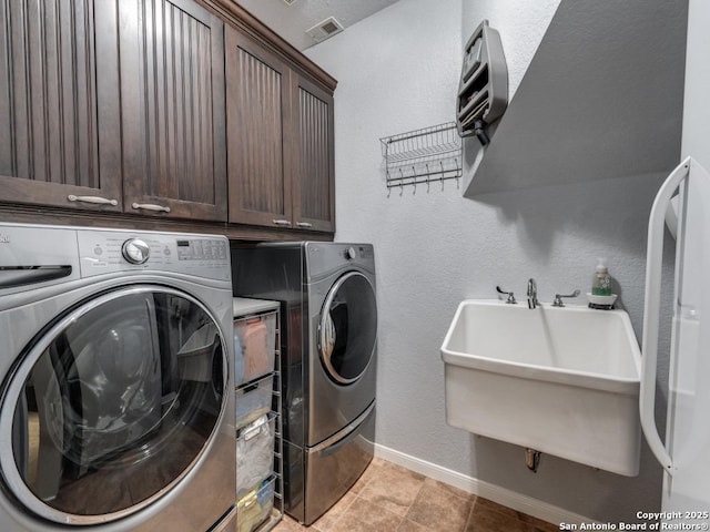clothes washing area featuring a sink, separate washer and dryer, and cabinet space