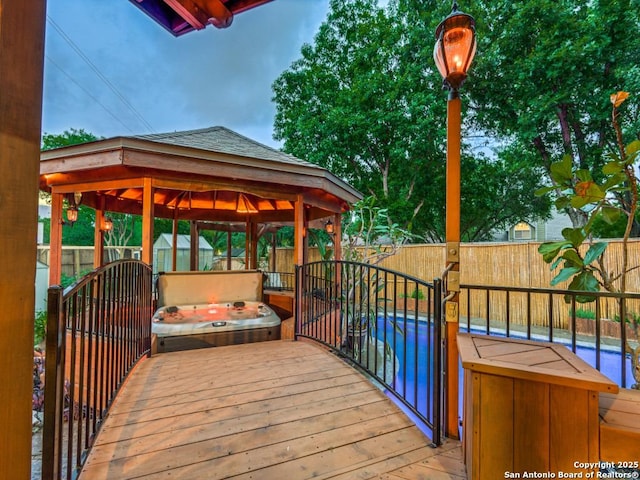 view of dock with a gazebo, a fenced backyard, a covered hot tub, and a pool